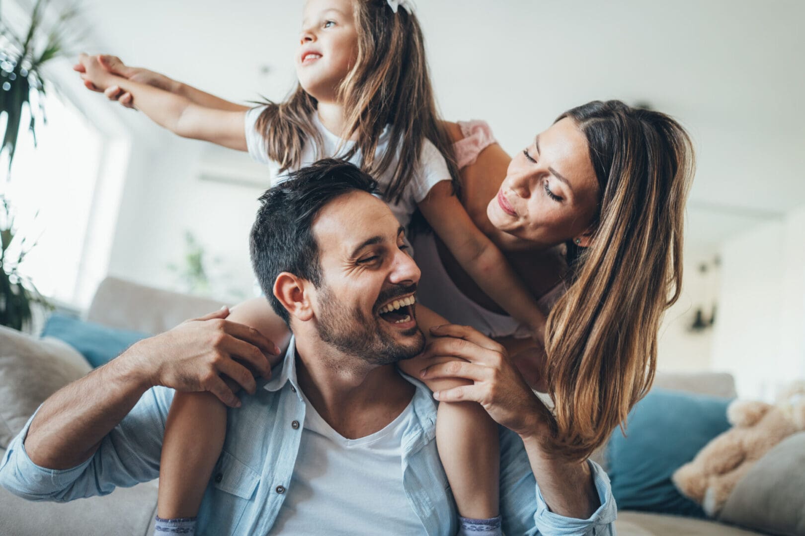 A young couple playing with their child who is sitting on his father's shoulders